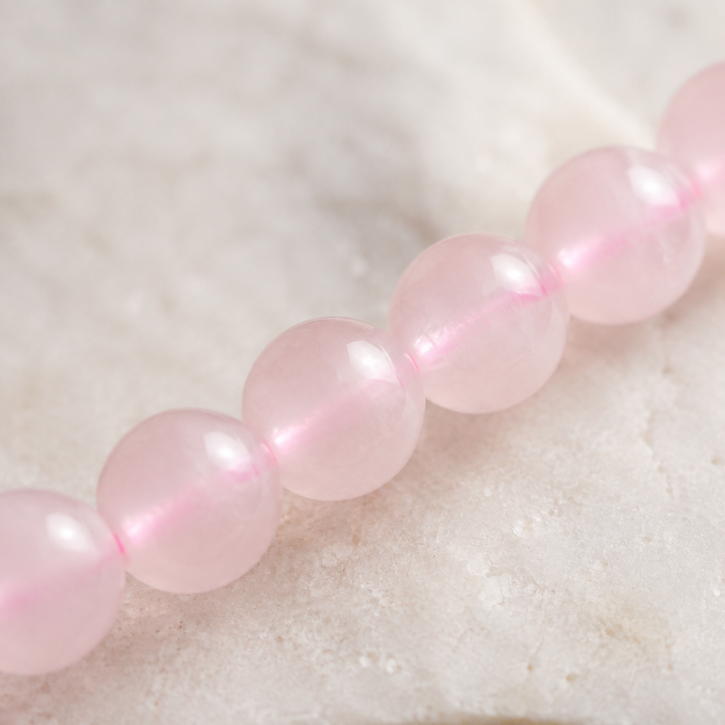 Gros plan sur les petites perles polies et le fil du collier en quartz rose