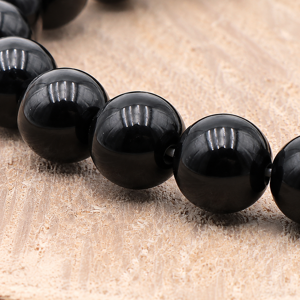 Gros plan sur les perles noires polies et le fil élastique du bracelet