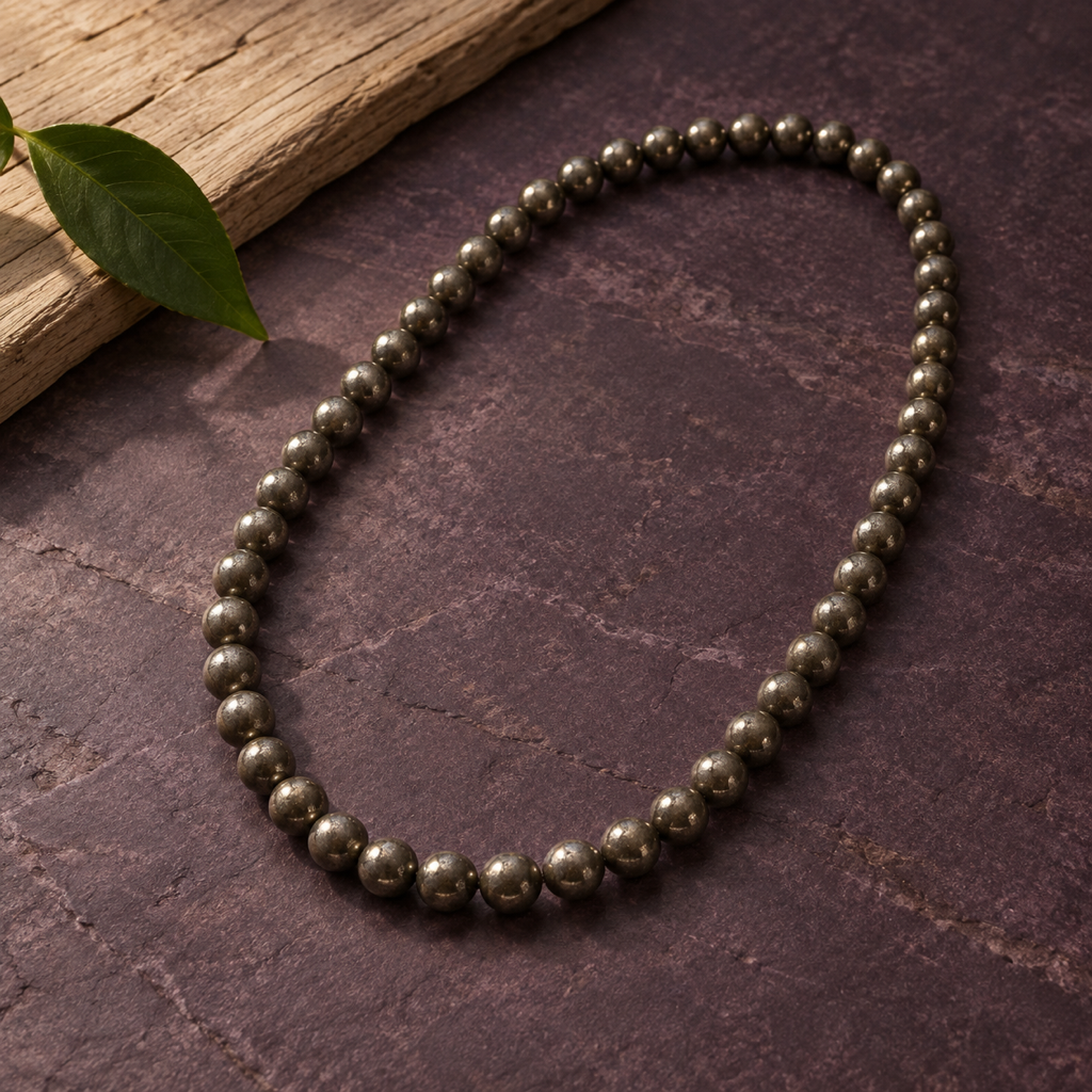 Collier en pyrite présenté sur pierre claire avec un feuillage discret