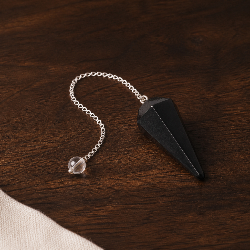 Pendule hexagonal en tourmaline noire, présentation sur une surface sombre contrastée