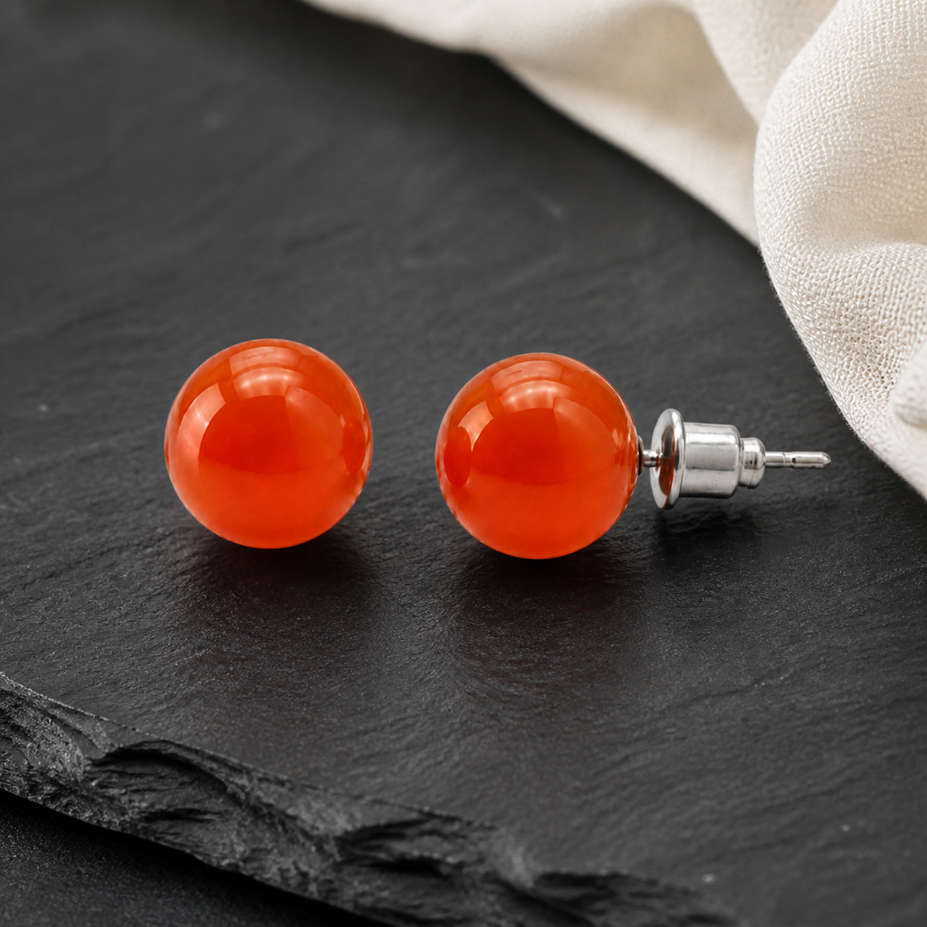Boucles d'oreilles puces en cornaline - 10 mm, présentation complète sur fond sombre contrasté