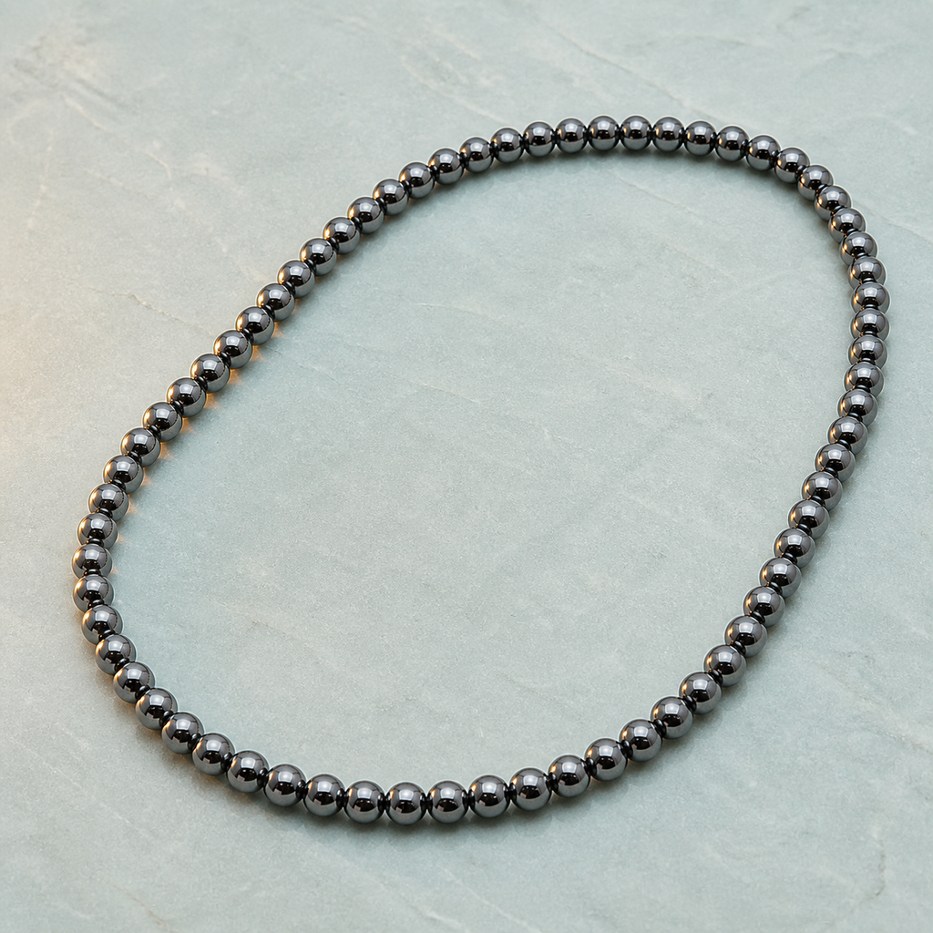 Collier en hématite 6 mm - 45 cm, présentation sur une surface sombre contrastée