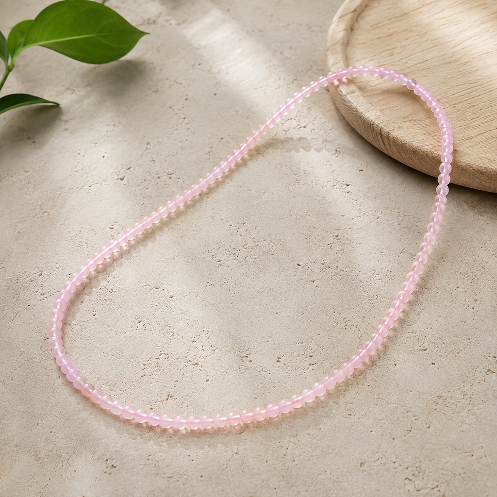 Collier en quartz rose sur un support contrasté avec une touche végétale