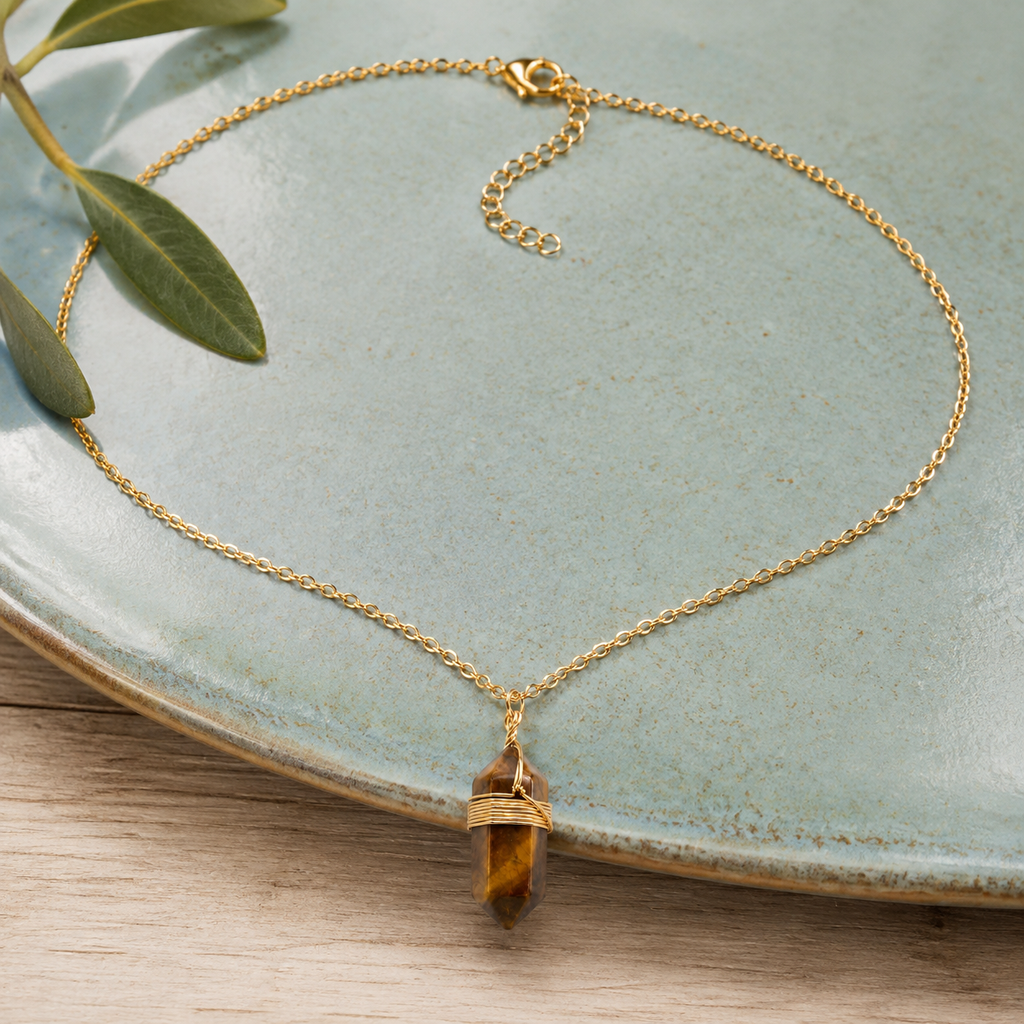 Collier doré en œil de tigre en nature morte près d’un feuillage
