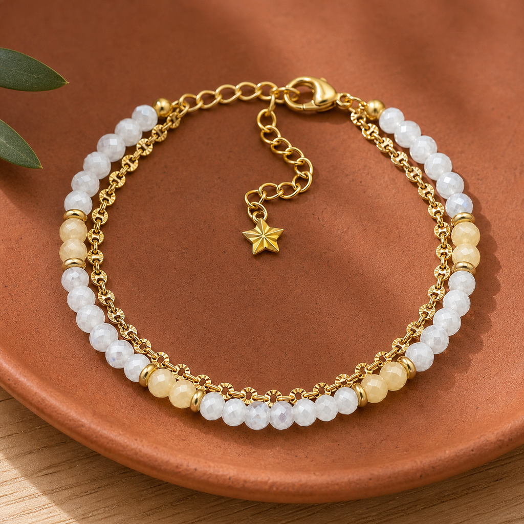 Bracelet doré en nacre et pierre de lune en nature morte près d’un feuillage