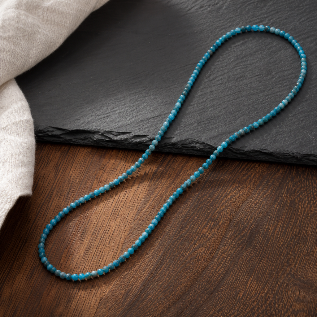 Collier en apatite bleue 4 mm - 45 cm, présentation sur une surface sombre contrastée