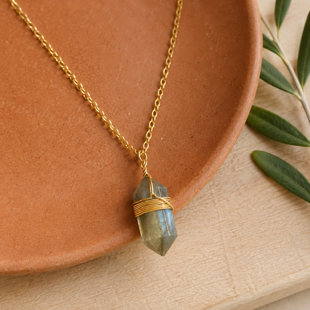 Collier doré en labradorite en nature morte près d’un feuillage