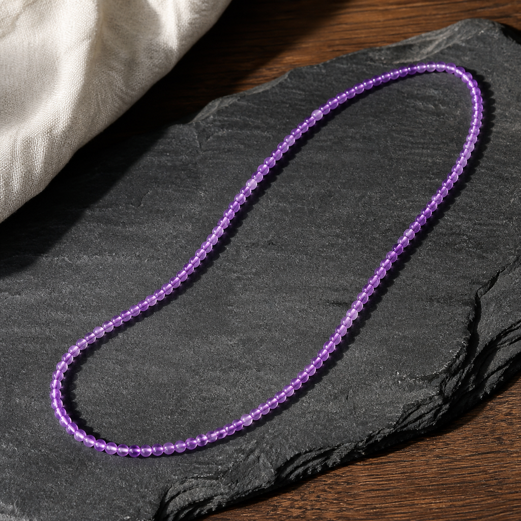 Collier en améthyste du Brésil 4 mm - 45 cm, présentation sur une surface sombre contrastée