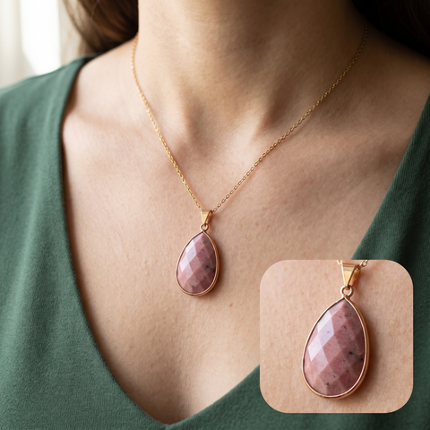 Pendentif ovale rose porté sur un haut vert forêt avec détail du serti doré