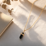 Collier obsidienne noire doré posé sur une coiffeuse claire