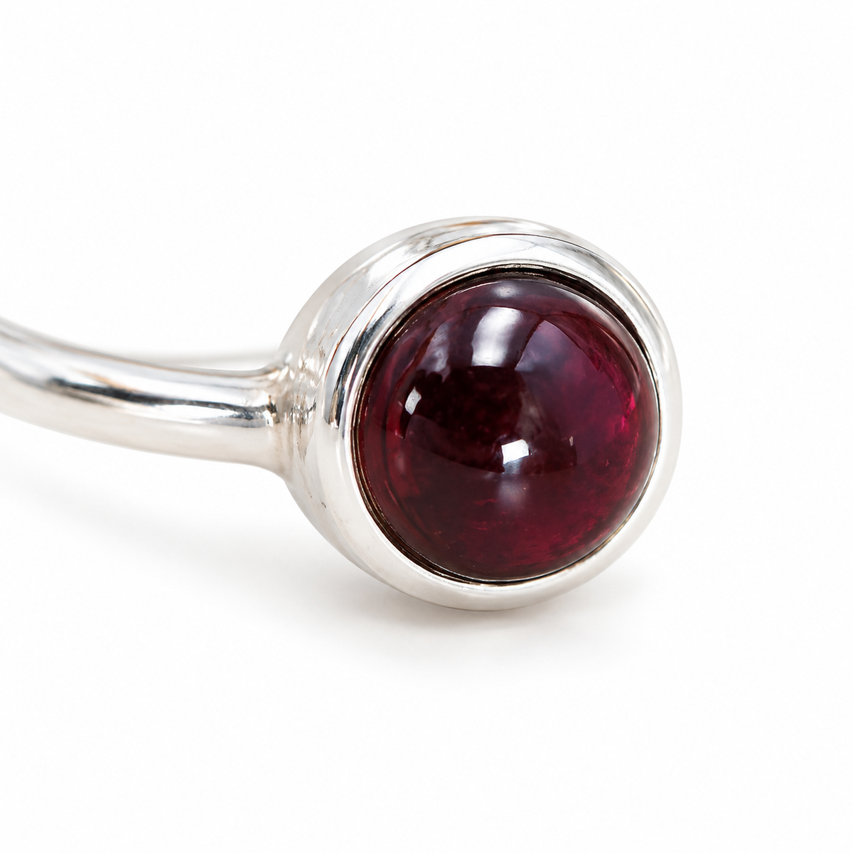 Détail du grenat rhodolite rond dans son serti en argent, avec l’anneau visible