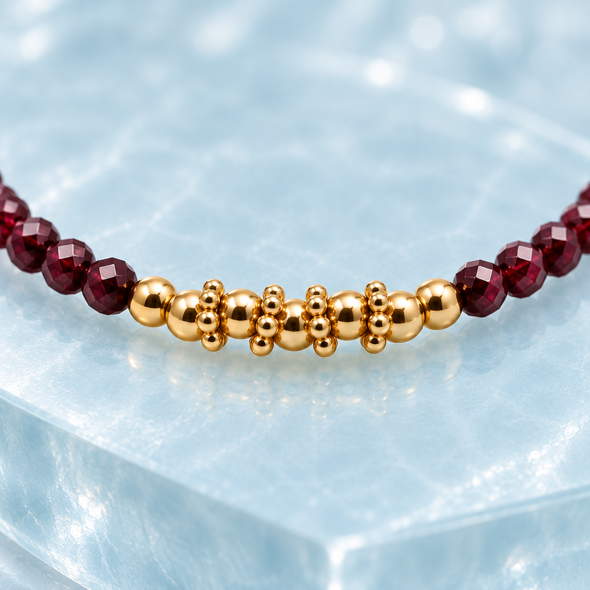 Détail carré des grenats rhodolites facettés et des éléments dorés du bracelet