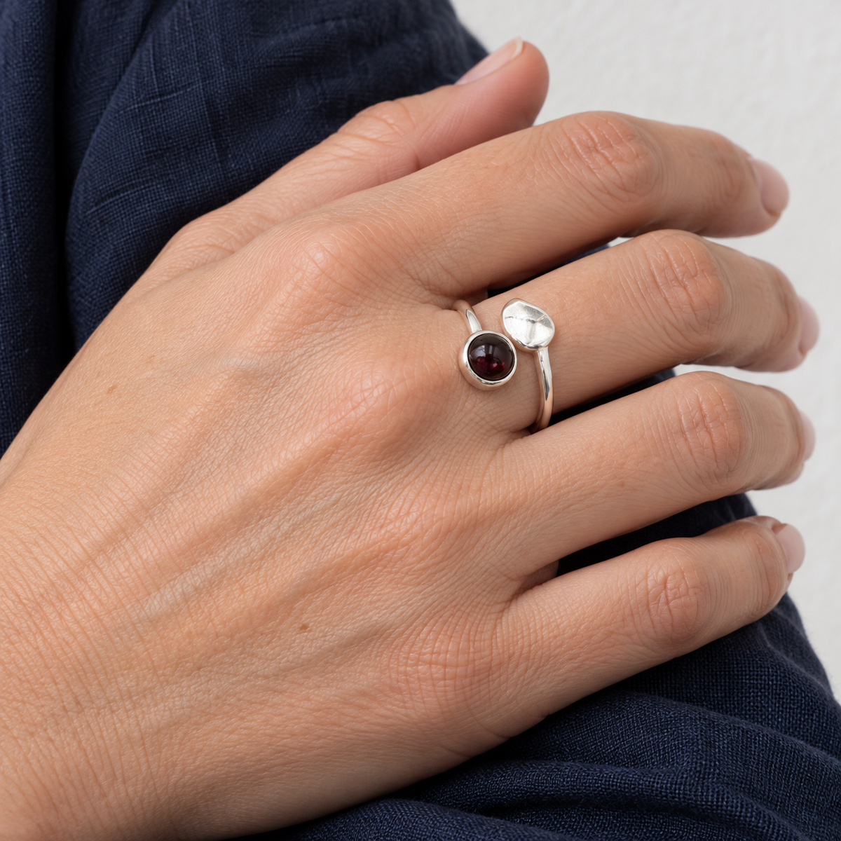 Bague au grenat rhodolite portée au quotidien, main au repos sur une manche bleu nuit