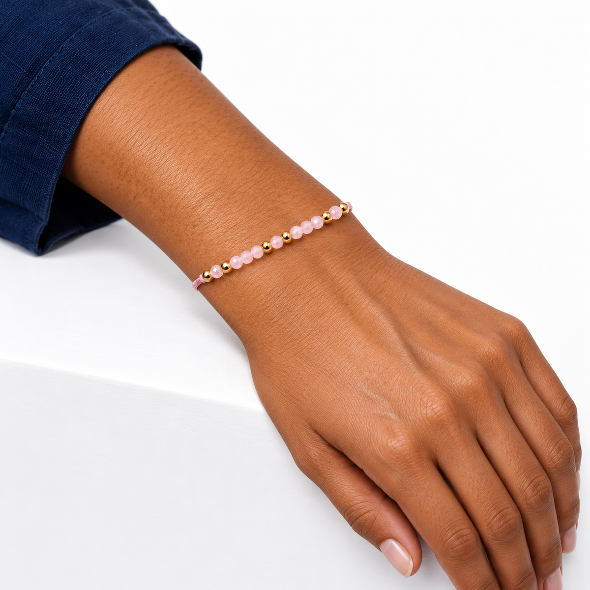 Bracelet en quartz rose porté, avant-bras posé sur un rebord blanc
